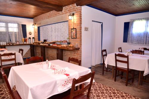 a restaurant with white tables and chairs and a counter at Pousada Vale da Mata in Pedra Azul