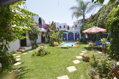 a yard with a swimming pool and a house at Riad Des Plages in Bouznika
