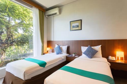 two beds in a hotel room with a window at Hotel Blambangan in Banyuwangi