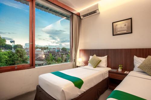 two beds in a room with a large window at Hotel Blambangan in Banyuwangi