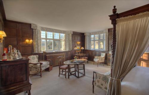 a bedroom with a bed and a table and chairs at Gravetye Manor in East Grinstead