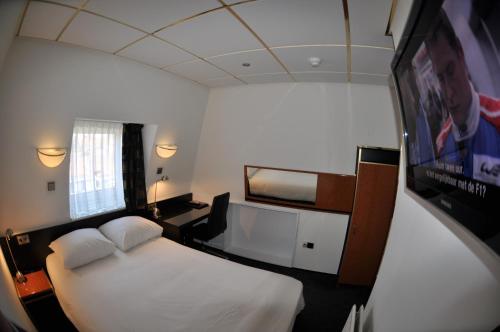 a hotel room with a bed and a flat screen tv at Budget Hotel Le Beau Rivage in Middelburg