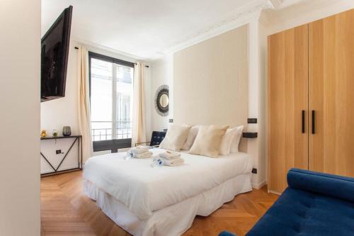 ein Schlafzimmer mit einem weißen Bett und einem blauen Sofa in der Unterkunft CMG Champs Elysees - Boetie 5 in Paris