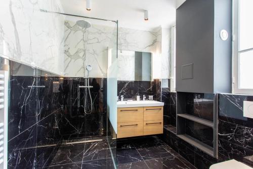 uma casa de banho com uma cabina de duche em vidro e um lavatório. em CMG Champs Elysees - Boetie 5 em Paris