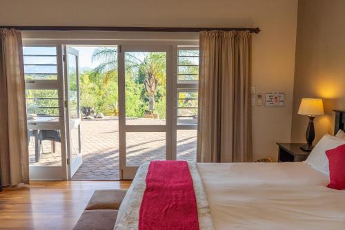 a bedroom with a bed and a sliding glass door at Aloe Manor in Oudtshoorn