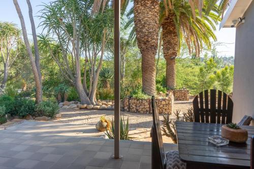 a patio with palm trees and a table and chairs at Aloe Manor in Oudtshoorn