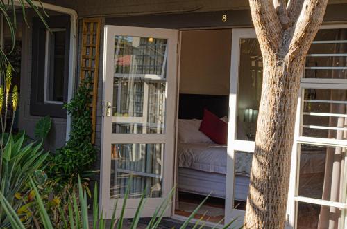 a room with a bed and a door with a tree at Aloe Manor in Oudtshoorn