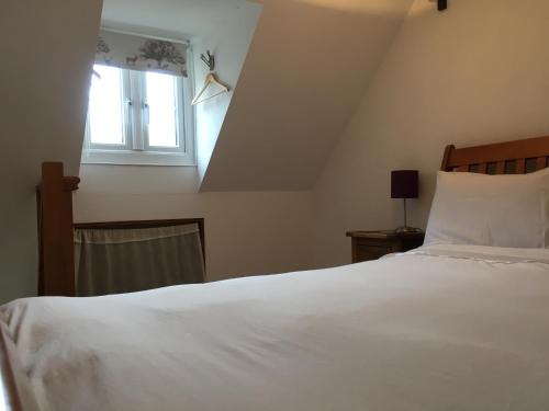 a bedroom with a white bed and a window at The Folly in Tetbury