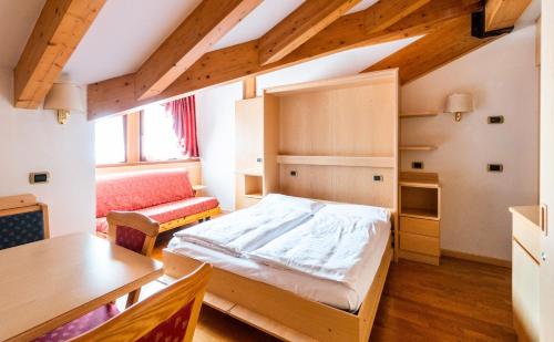 ein Schlafzimmer mit einem Bett, einem Tisch und einem Stuhl in der Unterkunft Garni Aritz in Campitello di Fassa