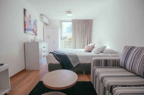 um quarto de hotel com uma cama e um sofá em Rentline Apartamentos - Skyline em Montevidéu