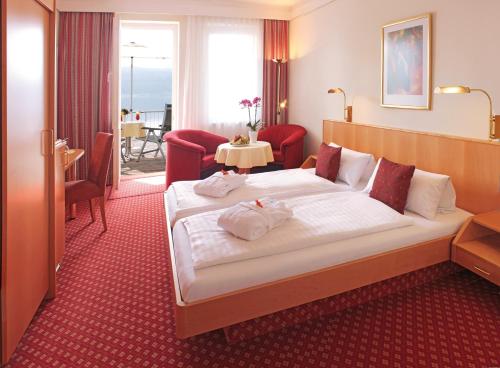 a hotel room with a large bed and a table at Strandhotel Löchnerhaus in Reichenau