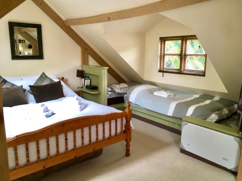 1 dormitorio en el ático con 2 camas y ventana en Greencourt Loft - The Cotswold Way, Stroud, en Stonehouse