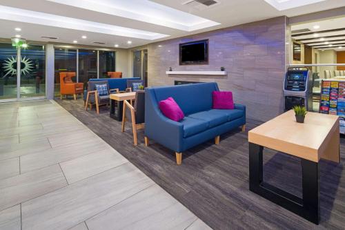 a waiting room with a blue couch and a table at La Quinta by Wyndham Orange County Airport in Santa Ana