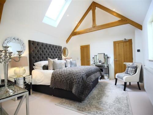 a bedroom with a large bed and a chair at The Hive in Stow on the Wold