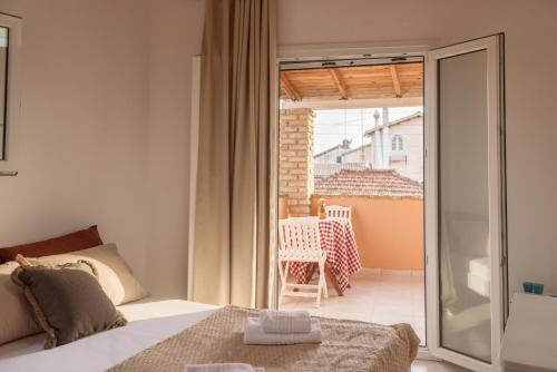 a bedroom with a bed and a balcony with a chair at Home Style Apartment in Lefkimmi