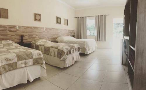 a hotel room with two beds and a brick wall at Pousada Pontal do Lago in Carmo do Rio Claro