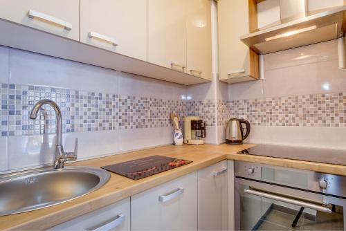 una cocina con armarios blancos y fregadero en Apartment Rosmarino, en Mali Lošinj