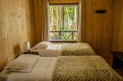 2 camas en un dormitorio con ventana en Cabañas Parque Michimahuida en Chaitén