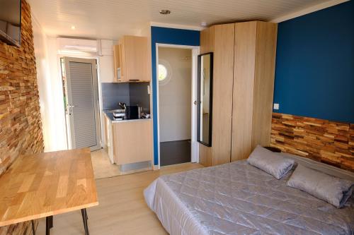 a bedroom with a bed and a table and a kitchen at Studio climatisé île naturiste du Levant in Hyères