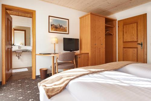 a bedroom with a bed and a desk with a television at Das Gertraud in Filzmoos