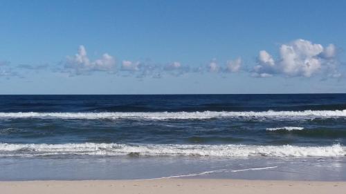 a beach with waves in the ocean with clouds in the sky at Pokoje Goscinne Bemar in Jastarnia