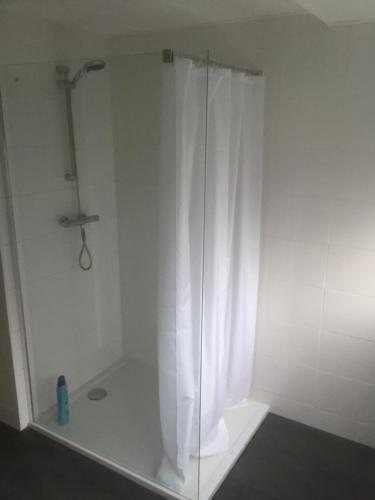 a shower with a curtain in a white bathroom at Op Nijverdal in Nijverdal