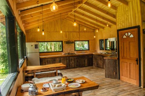 a large kitchen with wooden walls and a wooden table at Cabañas Parque Michimahuida in Chaitén