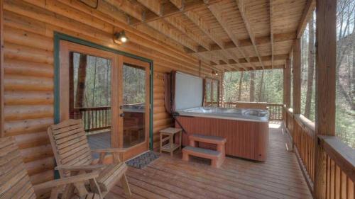 a porch of a log cabin with a tub and two chairs at Wilderness Way in Blue Ridge