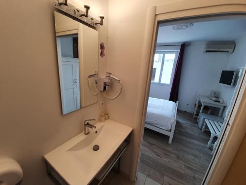 a bathroom with a sink and a mirror and a bed at Hôtel Les 3 Terrasses in Sari Solenzara