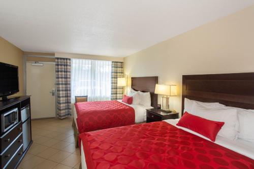 a hotel room with two beds and a flat screen tv at Ramada by Wyndham Venice Hotel Venezia in Venice