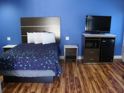 a bedroom with a bed and a flat screen tv at Oasis Inn Sacramento- Elk Grove in Sacramento