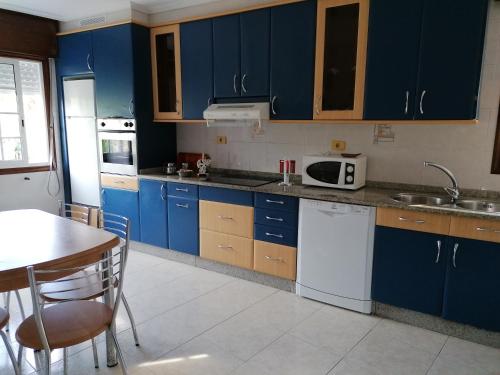 cocina con armarios azules, mesa y fregadero en Casa Ribe, en Tui