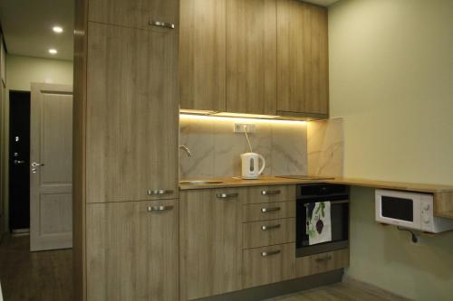 a kitchen with wooden cabinets and a microwave at EVA apartment in Vilnius