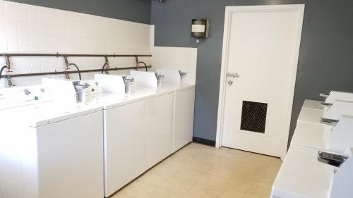 a bathroom with white sinks and a white door at Motel 8 Laramie in Laramie