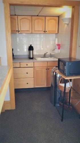 a kitchen with wooden cabinets and a microwave on a table at Motel 8 Laramie in Laramie
