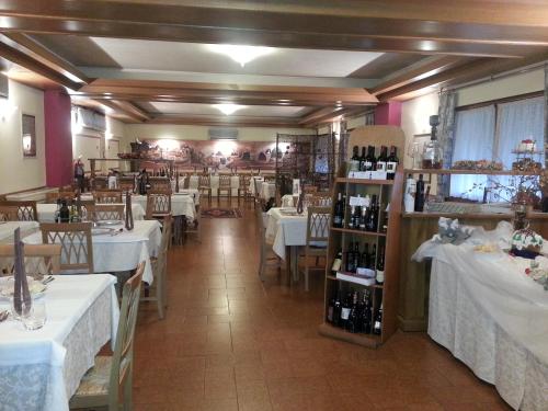 un restaurante con mesas y sillas y una habitación con botellas de vino en Albergo Ristorante Fratte, en Fregona