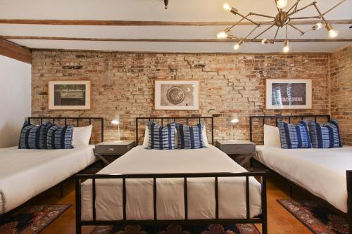 two beds in a room with a brick wall at LiivUP Warehouse Apartments in New Orleans