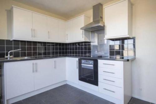 a kitchen with white cabinets and a black oven at Hillview home from home in Lackenby