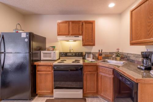 a kitchen with wooden cabinets and a black refrigerator at Woodlands on Fall River in Estes Park