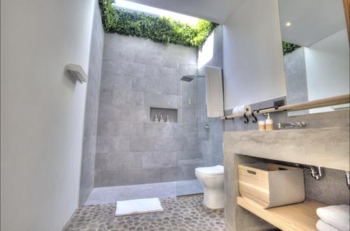 a bathroom with a shower with a toilet and a window at Garten Hotel in El Zonte