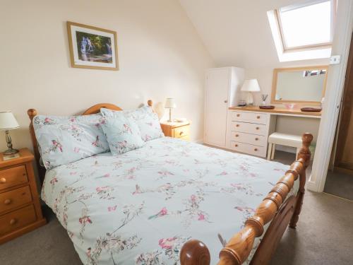a bedroom with a bed and a desk with a mirror at Ash Cottage in Llandysul