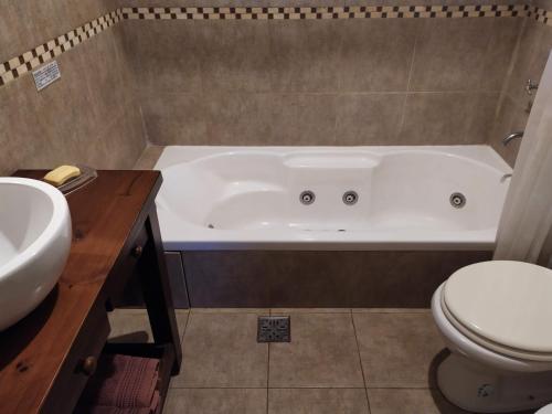 y baño con bañera, aseo y lavamanos. en Cabañas Las Primorosas en Cañuelas