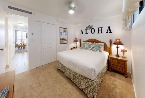 Dormitorio con cama con letrero de aloha en la pared en Kaanapali Shores - 943, en Lahaina