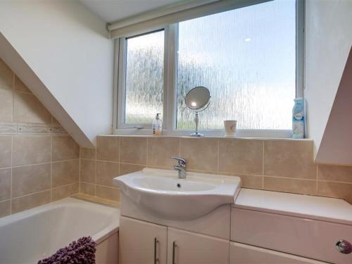 a bathroom with a sink and a window and a tub at The Cartins in Stroud