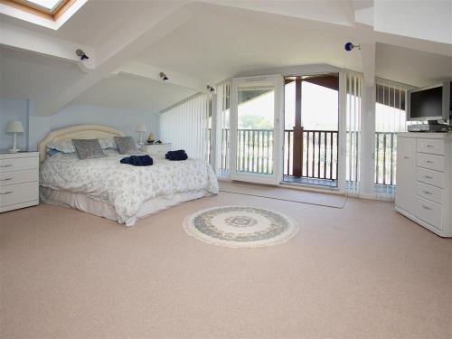 a white bedroom with a bed and a balcony at Gull's Rest in Seaton