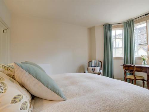 a bedroom with a bed with pillows and a table at The Old Dairy in Burford