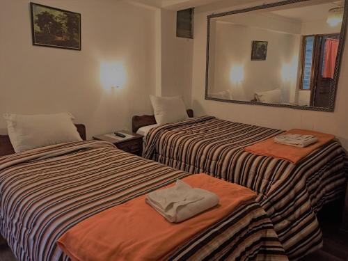 Hostal Tu Hogar في كوسكو: غرفة فندقية بسريرين ومرآة