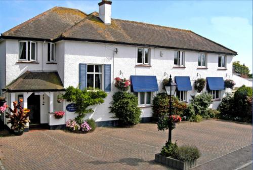 a white house with blue awnings on it at The Long Range in Budleigh Salterton