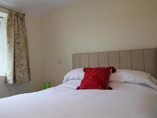 a red pillow sitting on top of a white bed at The Tractor Shed in Shaftesbury