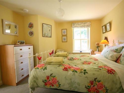 a bedroom with a bed and a dresser and a window at Garden Cottage in Alvescot